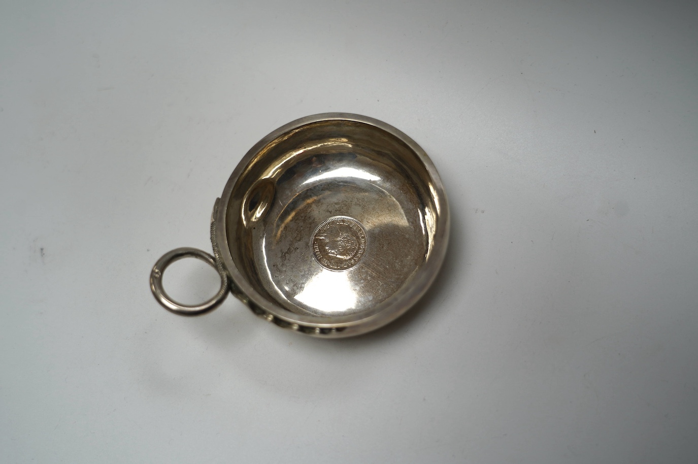 A 19th century French 950 standard white metal wine taster, with inset coin base, 11cm over handle, 99 grams. Condition - poor to fair